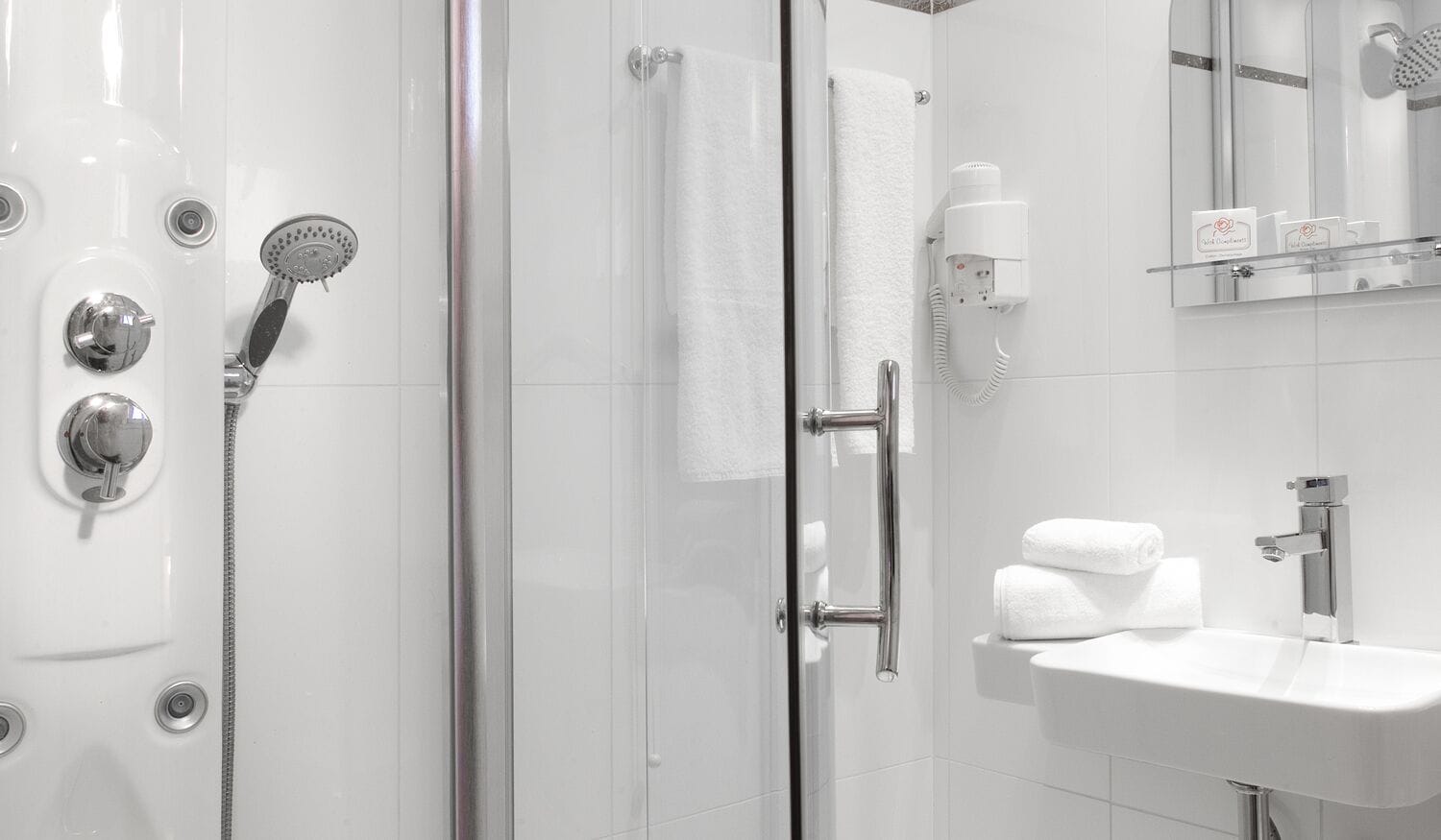 Un baño moderno con cabina de ducha de vidrio, un lavabo blanco y un perchero para toallas.