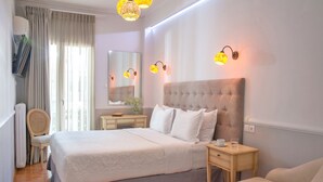 Moderni hotellihuone, jossa on suuri sänky, yöpöydät, tuoli, lipasto ja suuri peili.