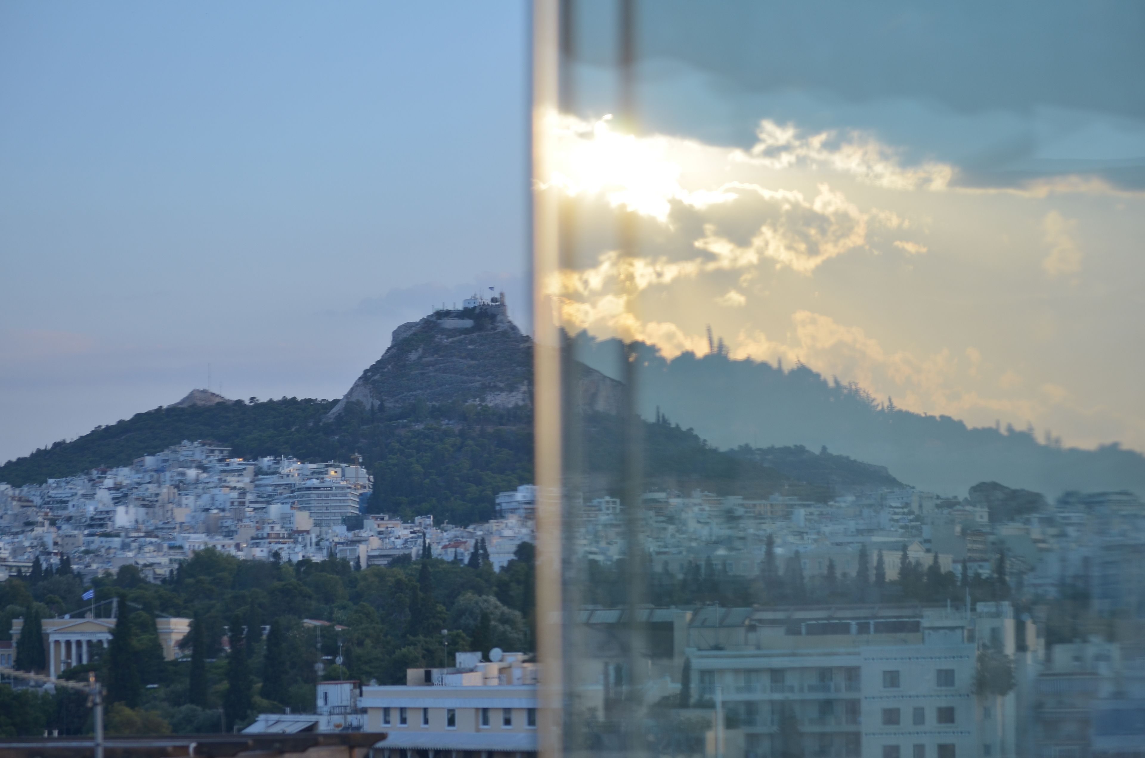 A cityscape with a prominent hill and a view of a building with a dome structure.