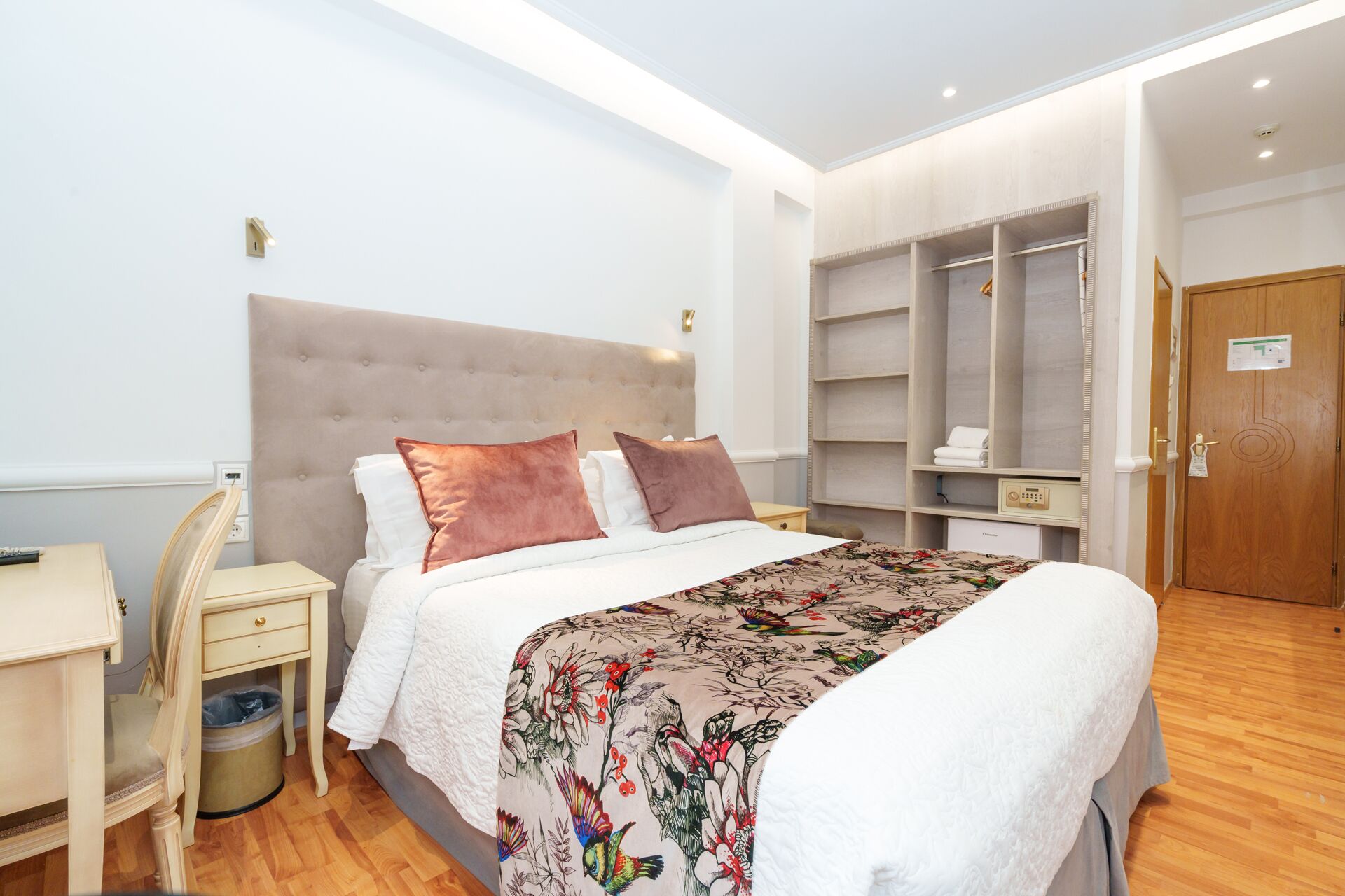 A hotel room with a large bed, a bedside table, a wardrobe, and a door.