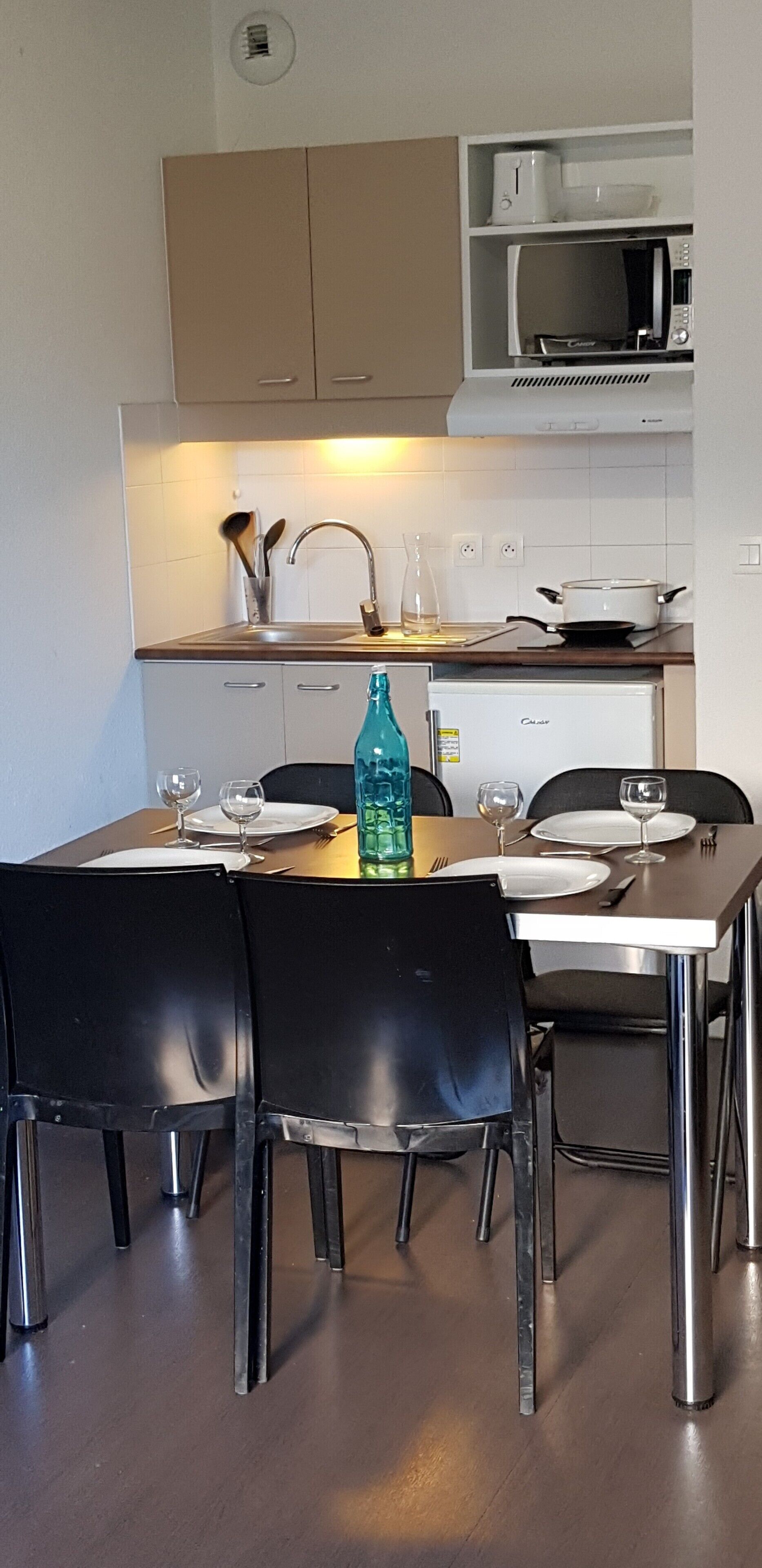 Un coin repas avec une table dressée pour quatre personnes, un four à micro-ondes placé au-dessus du comptoir et un placard en dessous.
