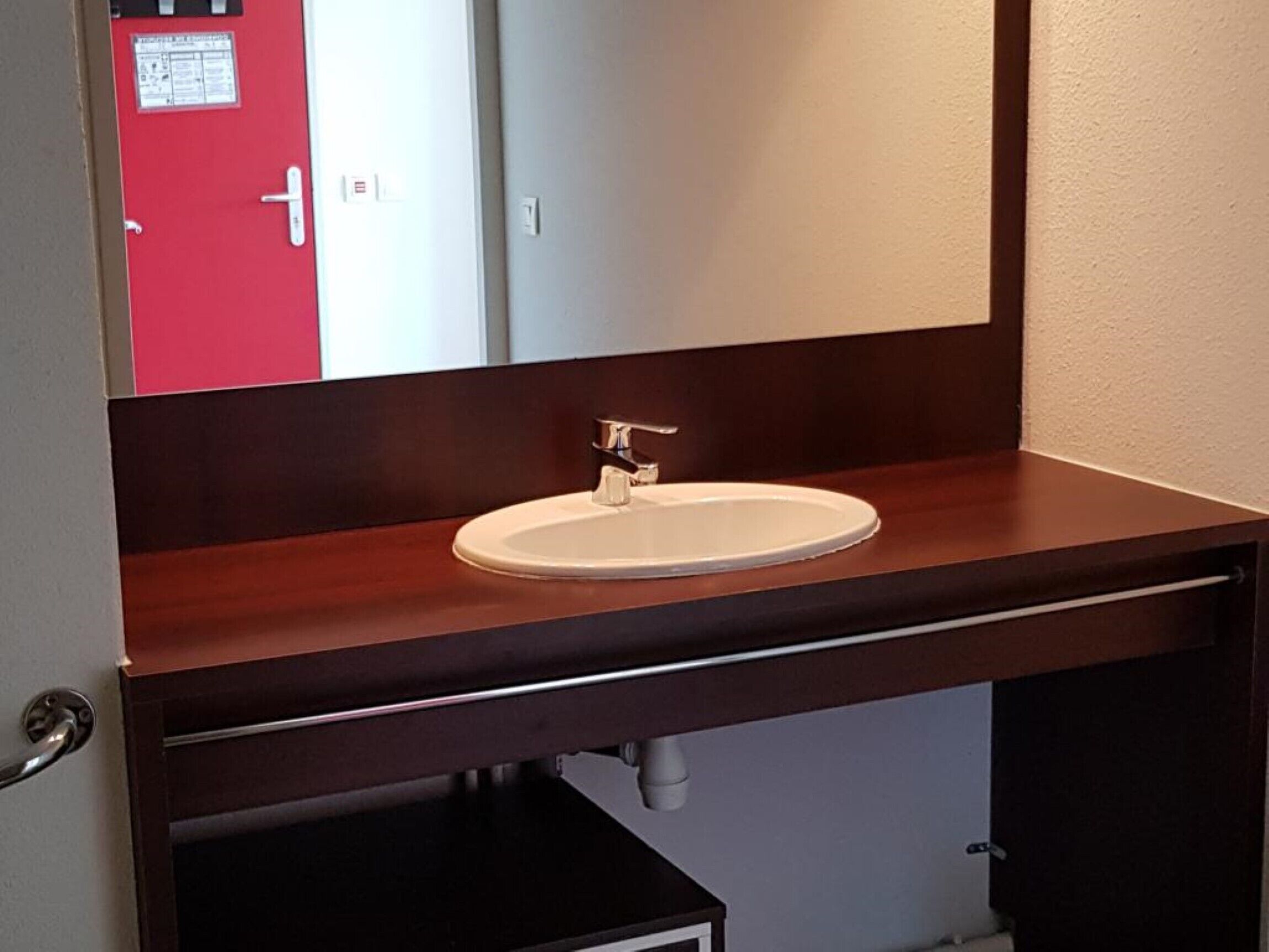 Une salle de bain avec un meuble-lavabo en bois, un lavabo blanc et un miroir au-dessus.
