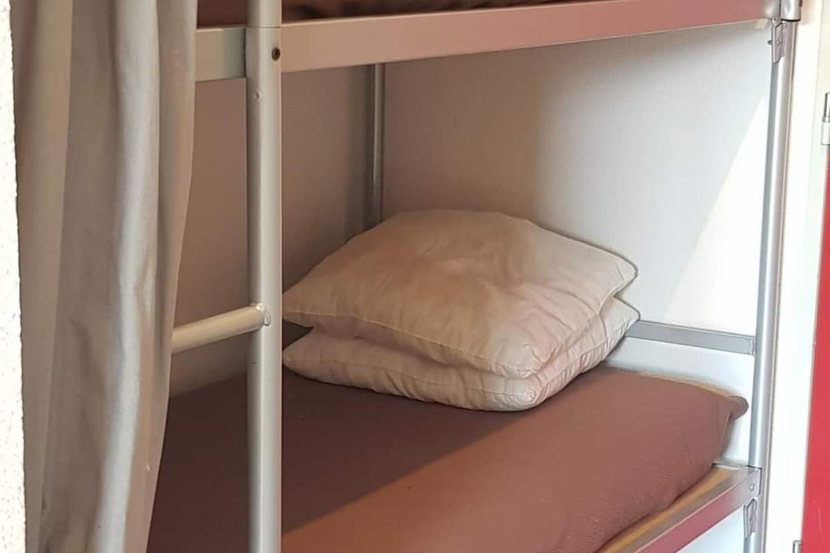 A bunk bed with a single pillow on the lower bunk.