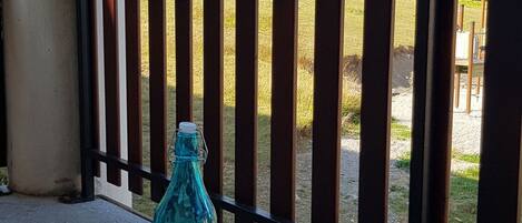 Une bouteille bleue et un verre sur un balcon doté d’une rambarde en bois.