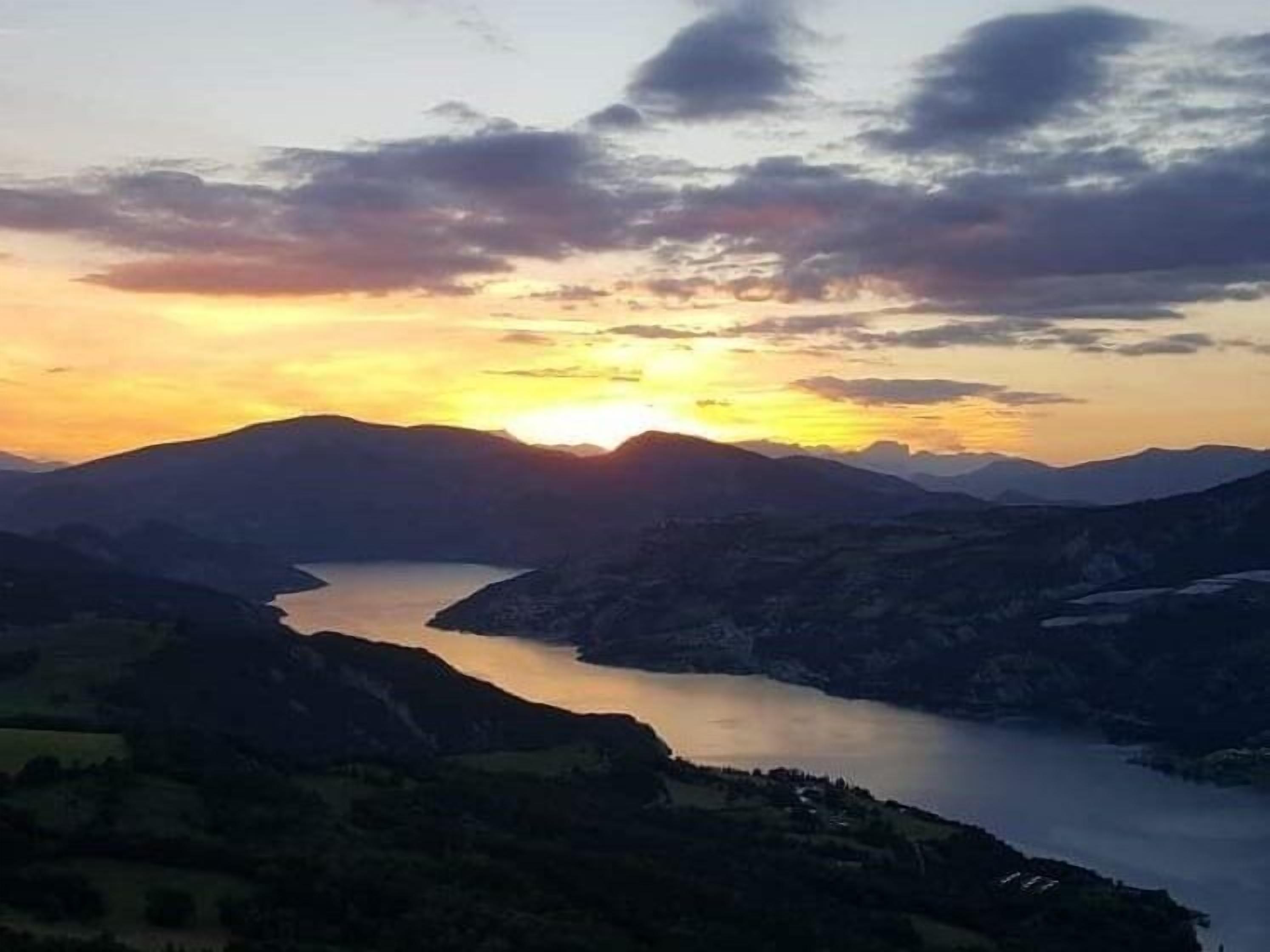 Un paisatge de muntanyes amb un riu al capvespre.
