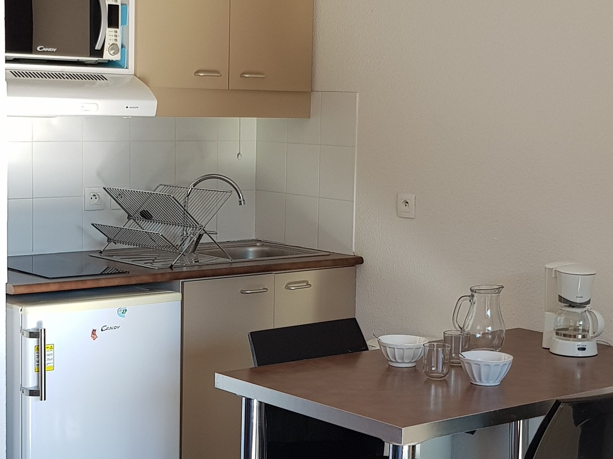 Une cuisine compacte équipée d’un four à micro-ondes, d’un évier et d’une machine à café posée sur le plan de travail.
