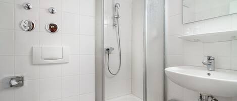 A modern bathroom with a glass-enclosed shower, a white sink, and a toilet.