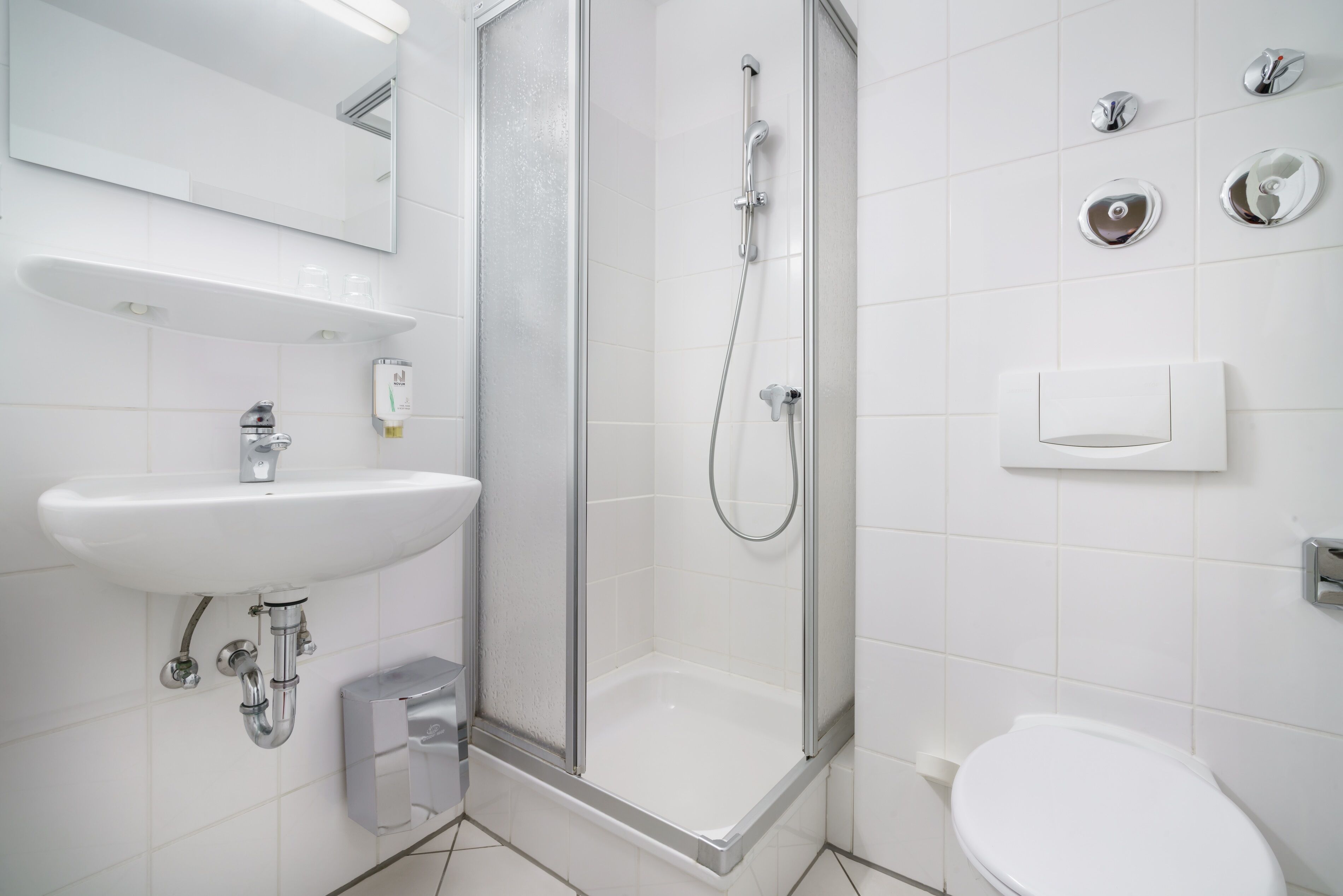 A modern bathroom with a glass-enclosed shower, a white sink, and a toilet.