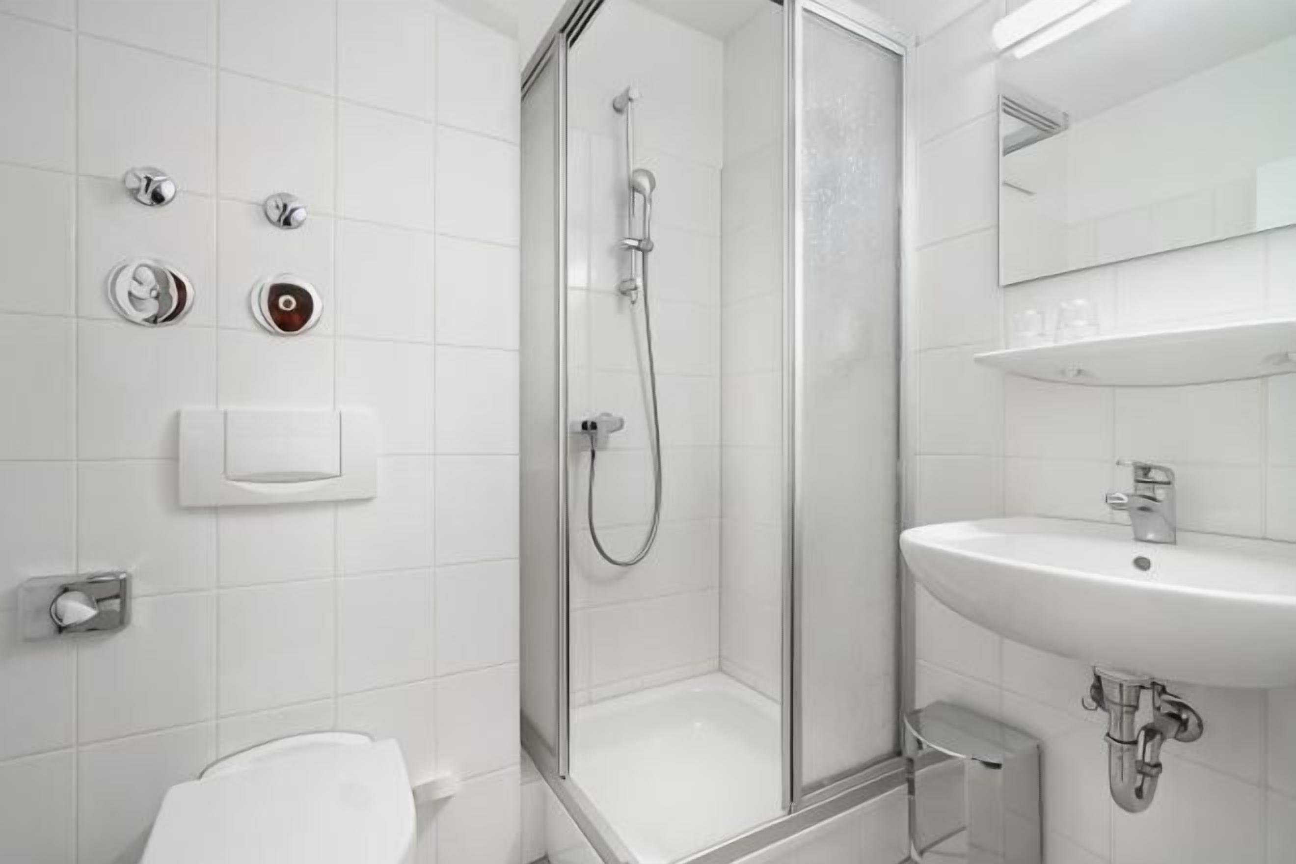 A modern bathroom with a glass-enclosed shower, a white sink, and a toilet.