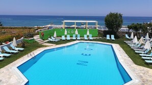 En pool med utsikt över havet, omgiven av solstolar och parasoller.