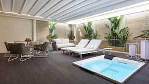 Un espace de détente extérieur moderne, doté d’une piscine, de sièges et de plantes en pot.
