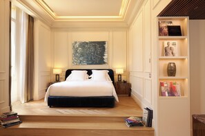 A hotel room with a large bed, a bookshelf, and a painting on the wall.