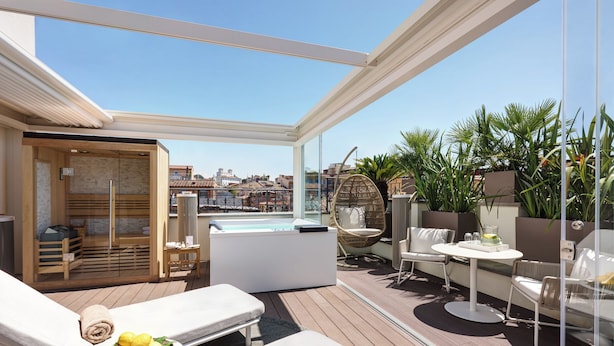 Une terrasse sur le toit équipée de chaises longues, d’un jacuzzi et d’un espace repas.