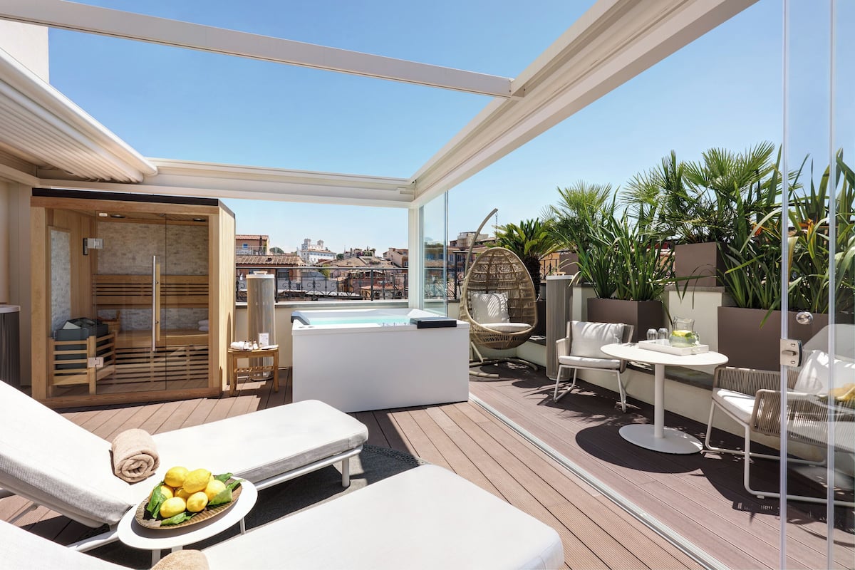 A rooftop terrace with sun loungers, a hot tub, and a dining area.