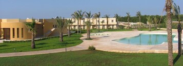 Un resort con piscina, palmeras y un edificio de techo plano.