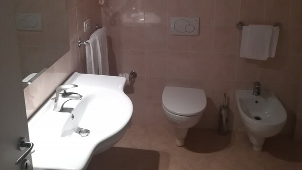 Une salle de bain équipée d’un lavabo, de toilettes, d’un bidet et d’un miroir.