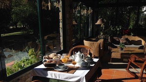 Un comedor con una mesa dispuesta para el desayuno, mobiliario de mimbre y vistas al exterior.