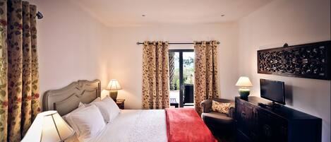 Habitación de hotel con cama, dos lámparas de noche, televisor, cómoda y vista al exterior.