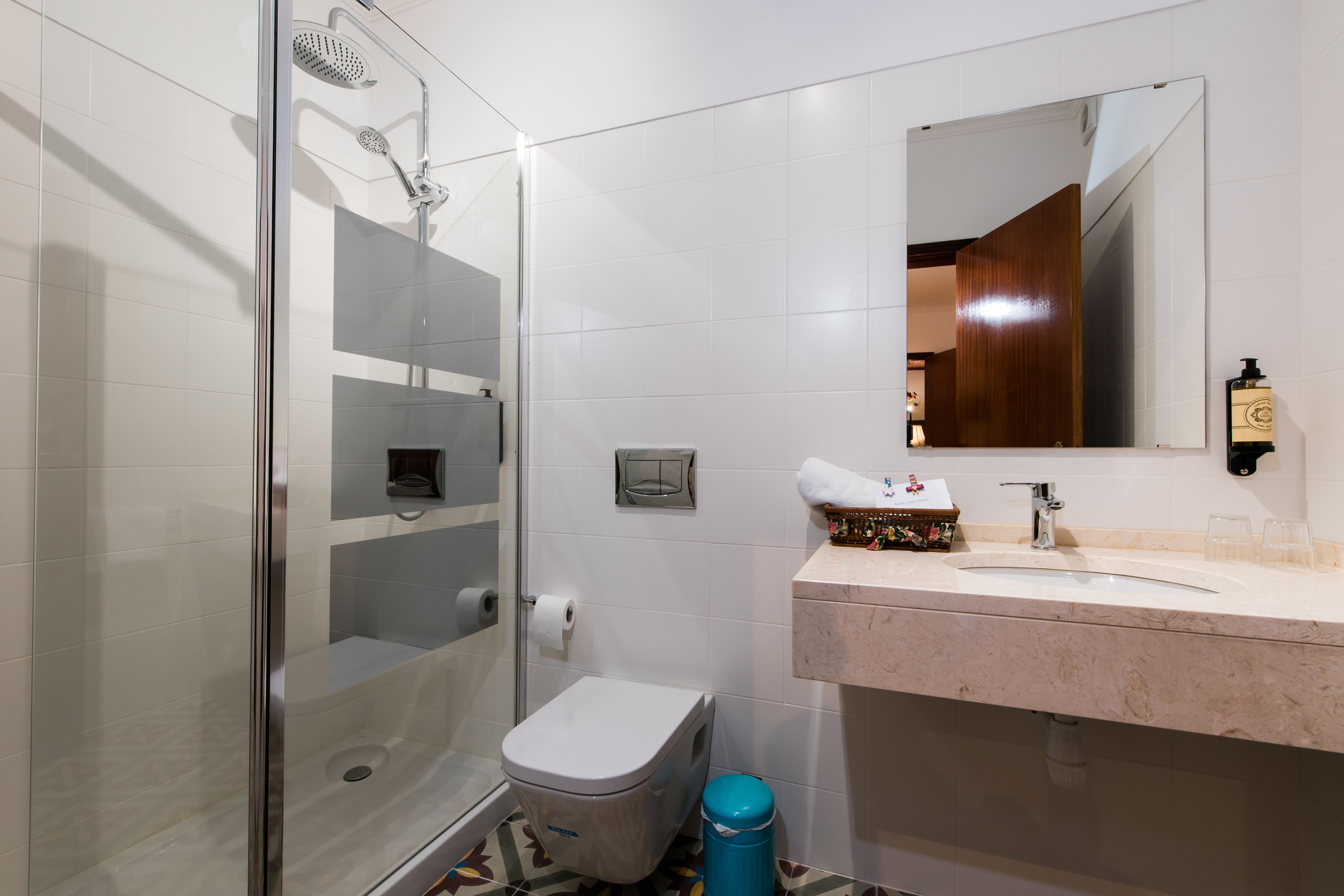 Une salle de bain moderne avec une douche à parois de verre, des toilettes, un lavabo avec un miroir et une poubelle.