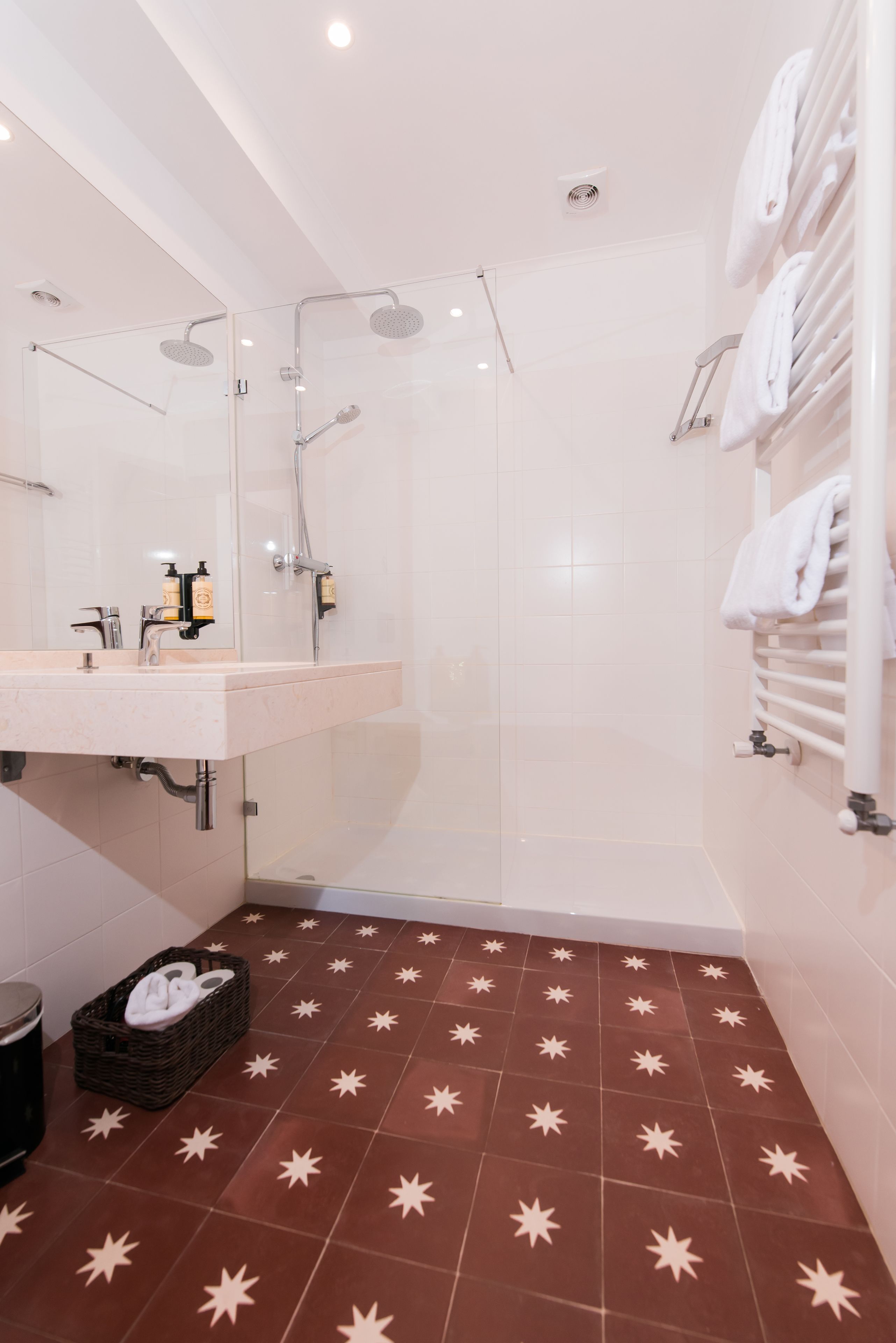 Un baño moderno con ducha de vidrio, tocador con espejo y perchero para toallas.
