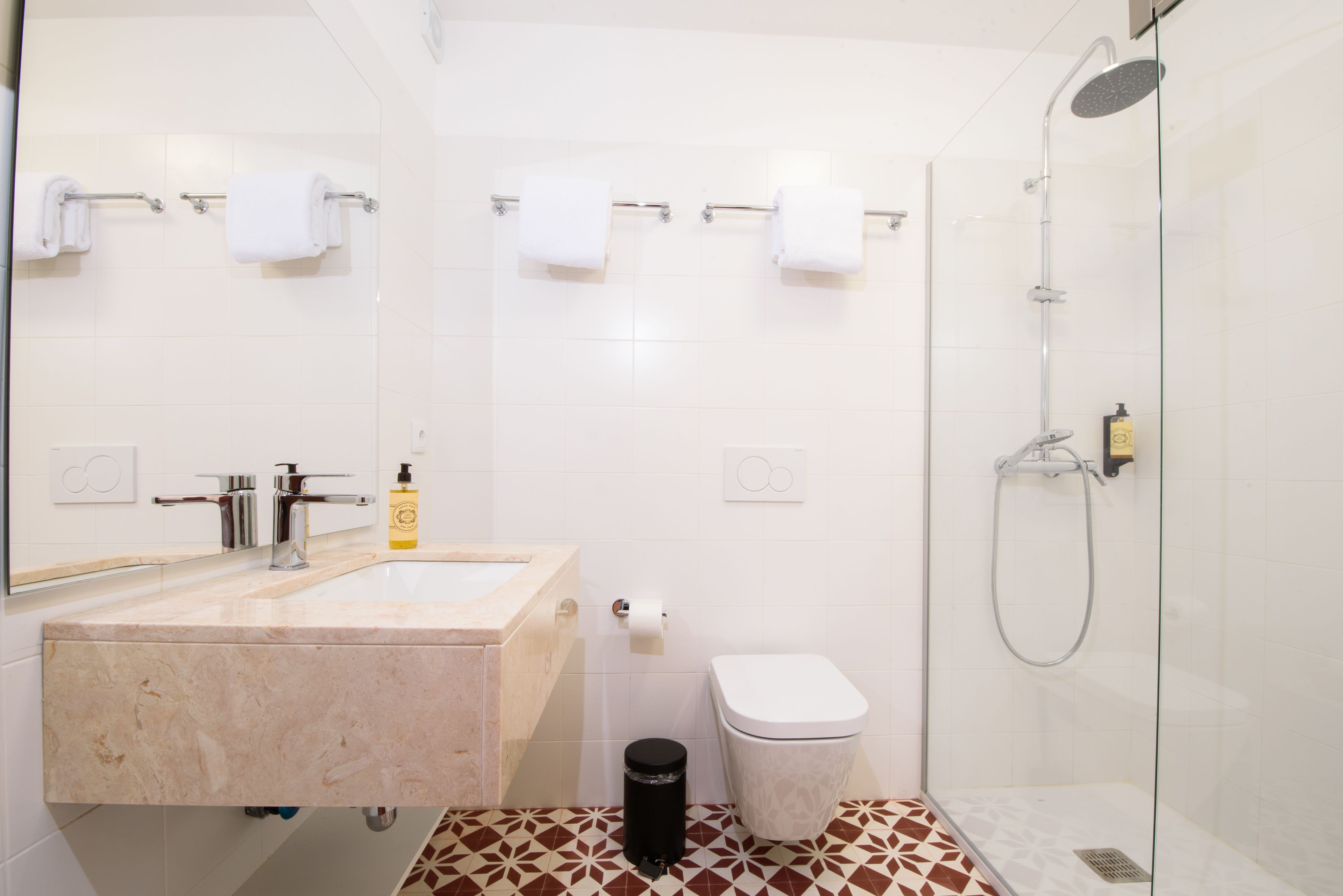A modern bathroom with a marble sink, a toilet, and a glass-enclosed shower.