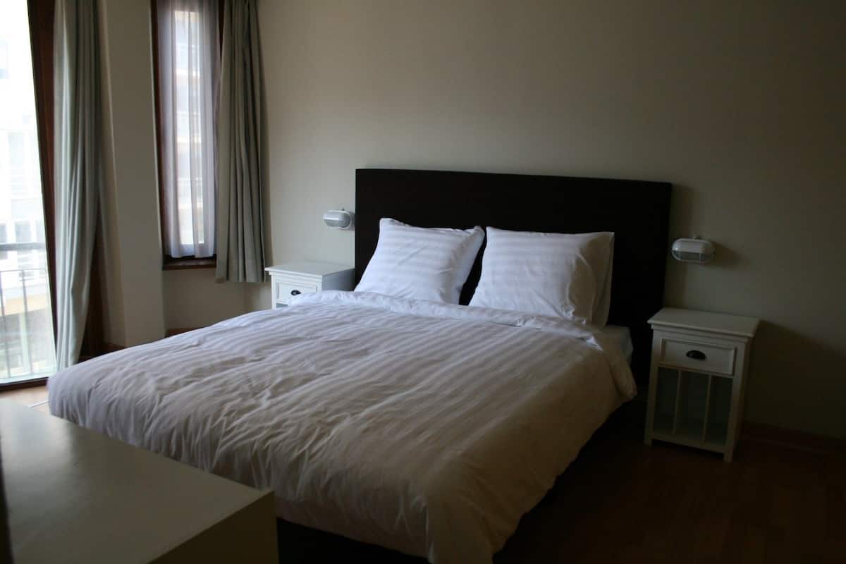 Un lit bien fait, avec du linge de lit blanc, dans une chambre d’hôtel.