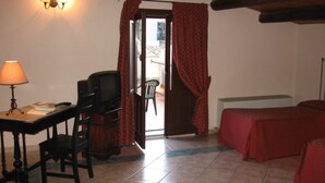 A room with a desk, chair, television, and a bed. - Albergo La Fontanella (Noto)