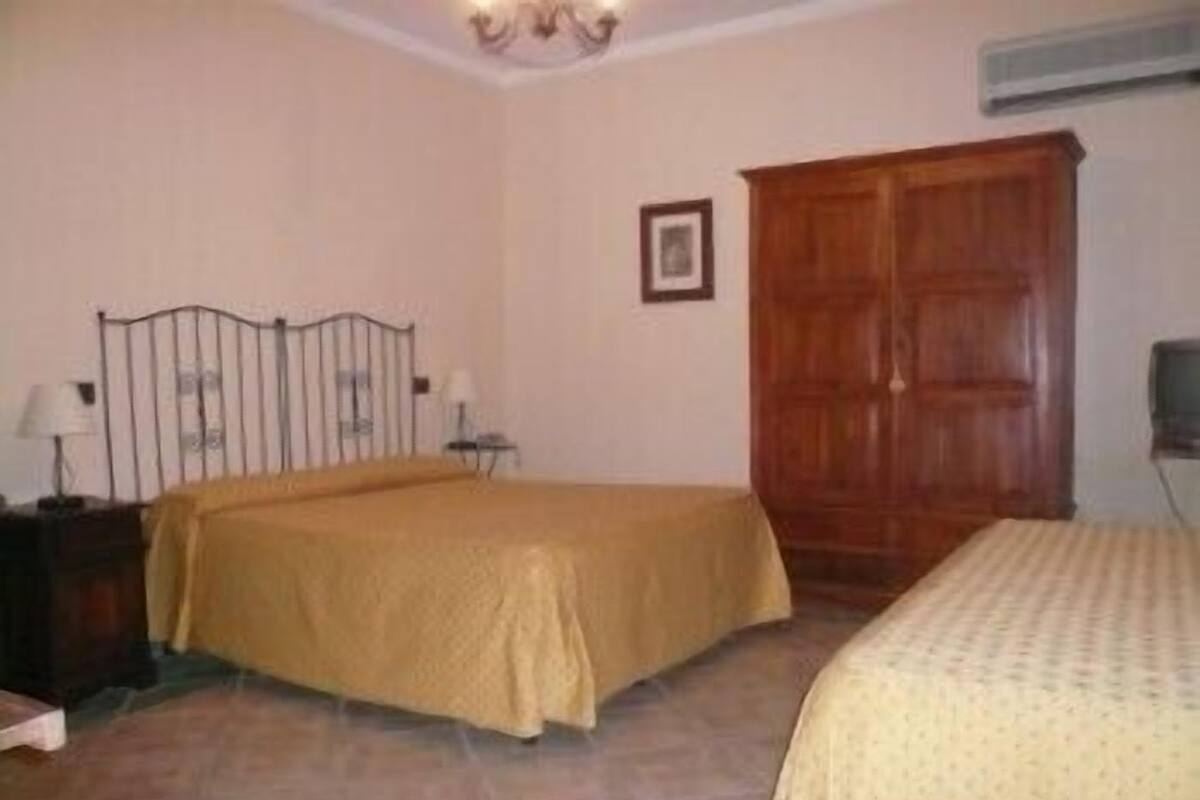 Un dormitorio con cama, armario, mesita de noche y aire acondicionado de pared.