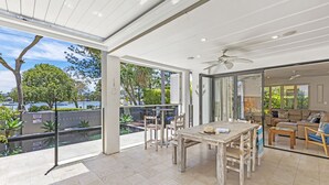 Un patio amplio con mesa y sillas, un ventilador de techo y vistas al exterior.