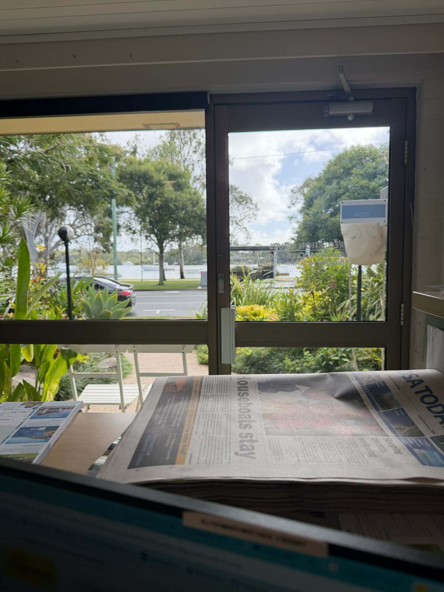 A room with a window overlooking a street and greenery.