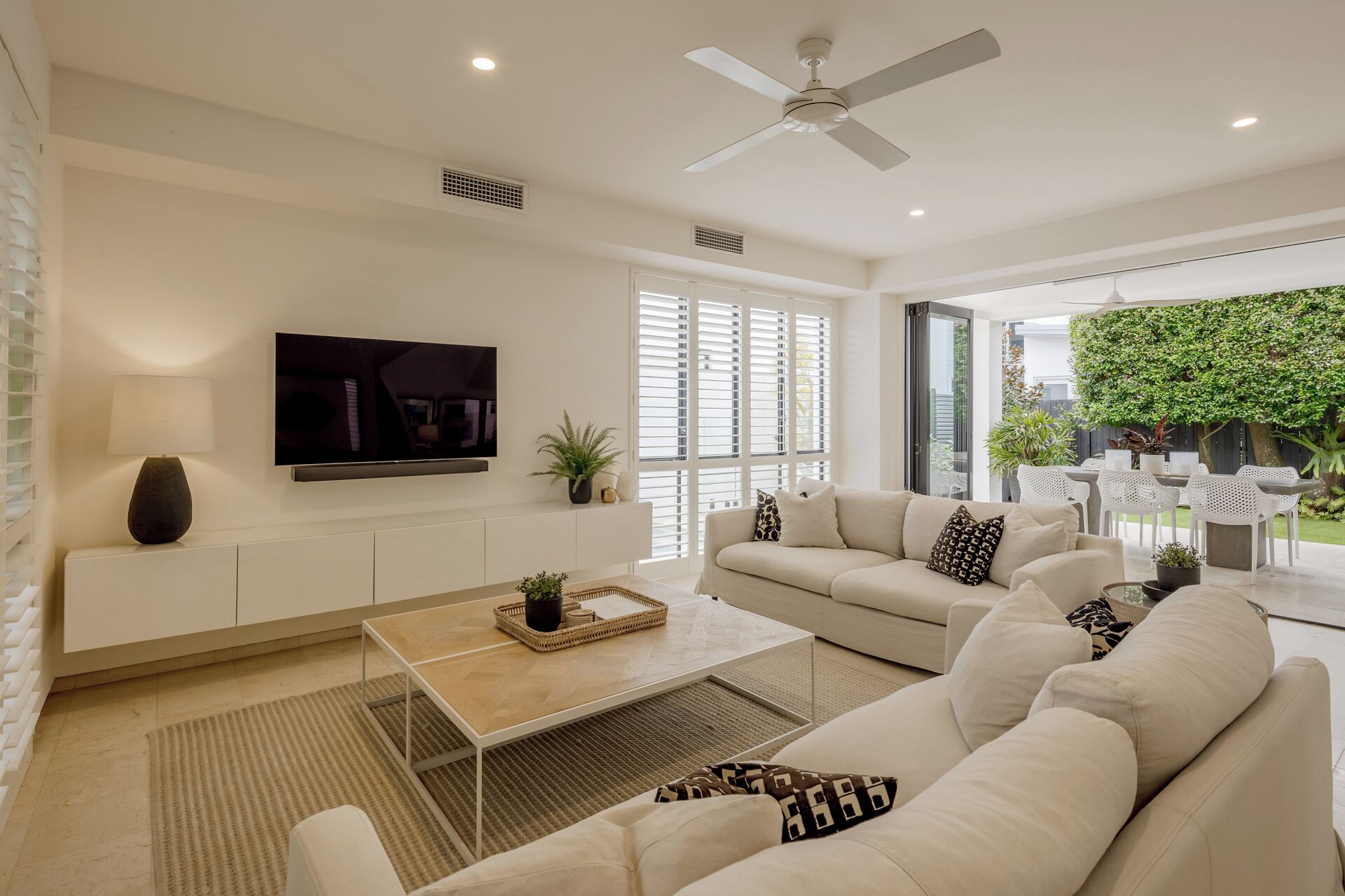 Una sala de estar moderna con sofá, mesa de centro, televisor y vistas al exterior.