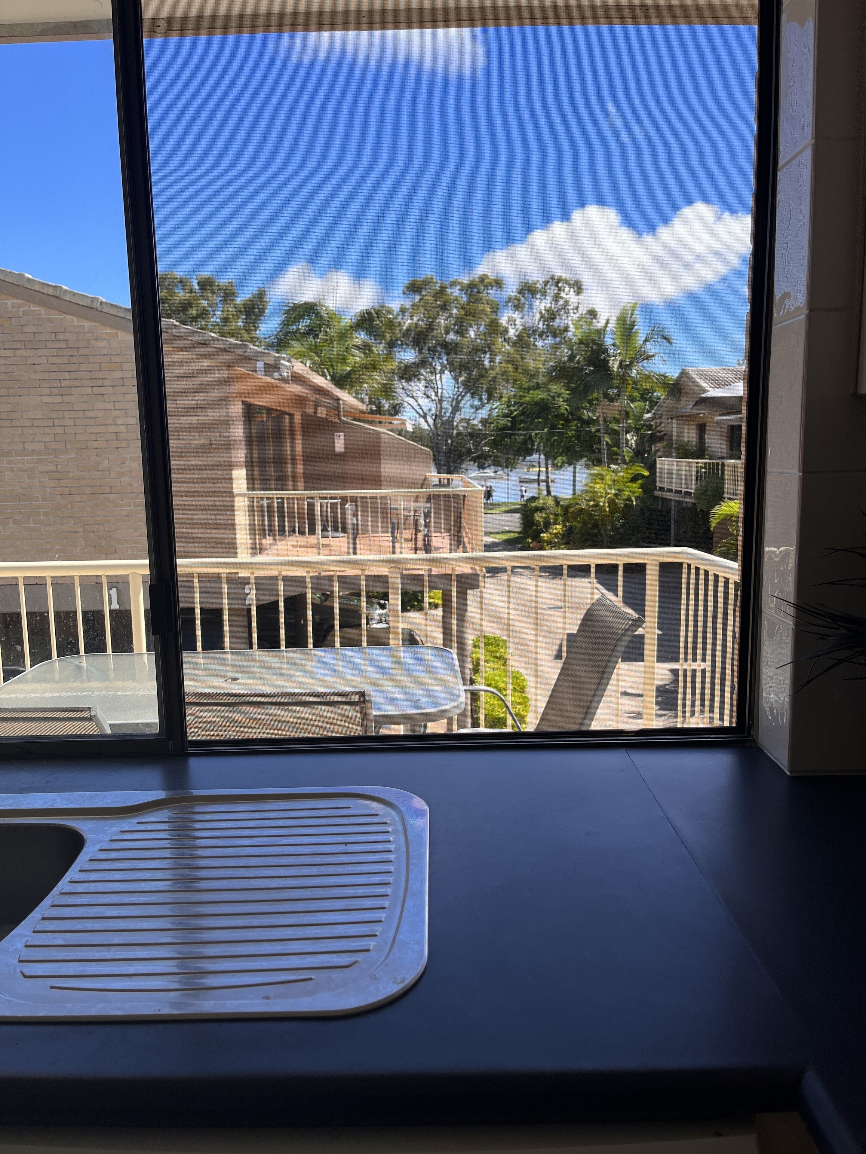 Un balcone con vista su una zona residenziale, una sedia e un tavolino.
