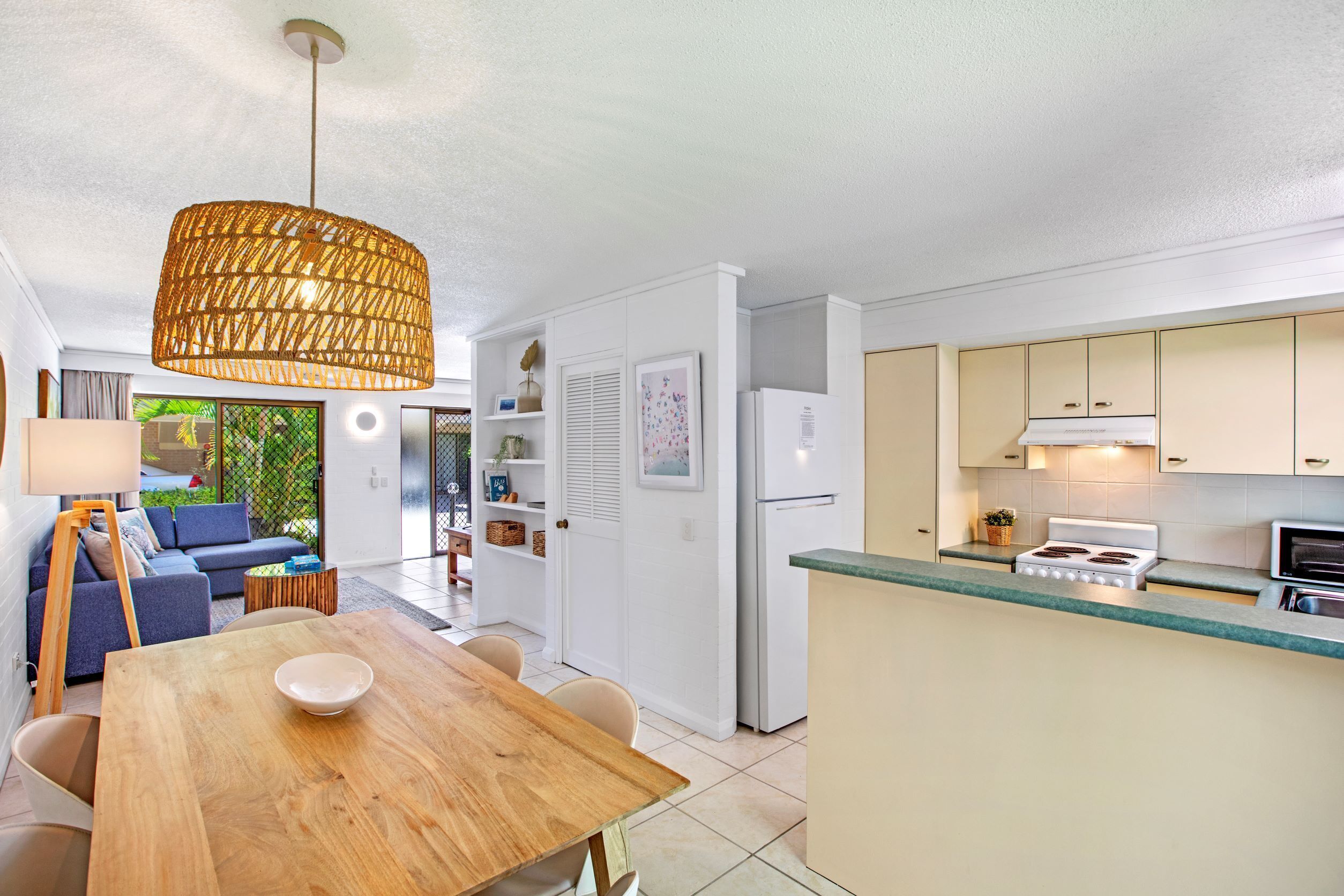 A modern kitchen with white cabinets, a built-in stove, and a dining area with a wooden table and chairs.