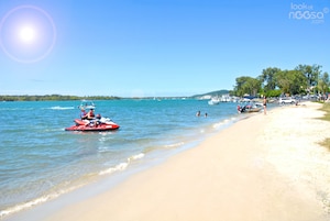 Una playa con agua azul cristalina, una orilla arenosa y barcos.