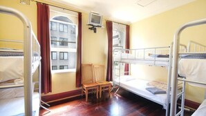 A room with bunk beds, a television, a chair, and a window with curtains. - Sydney City Hostel (Haymarket)