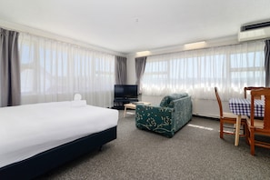 Una habitaci ón de hotel con una cama, un sofá, un televisor y una silla.