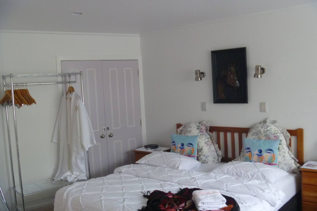 A bedroom with a bed, a wardrobe, a nightstand, and a painting on the wall.