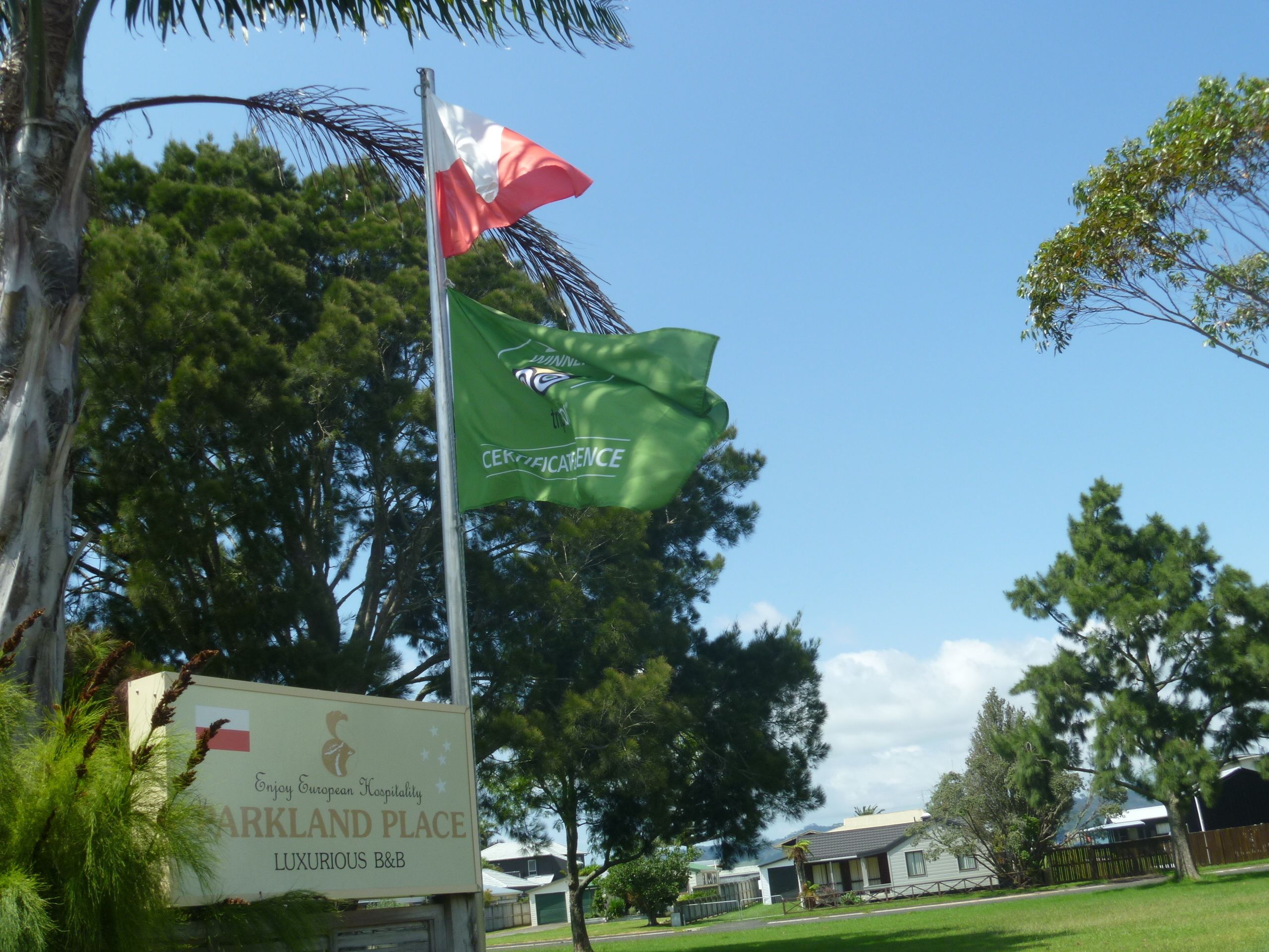 Une enseigne indiquant « ARKLAND PLACE », avec un mât sur lequel flotte un drapeau et un drapeau vert portant l’inscription « CEKZAFICENCE ».