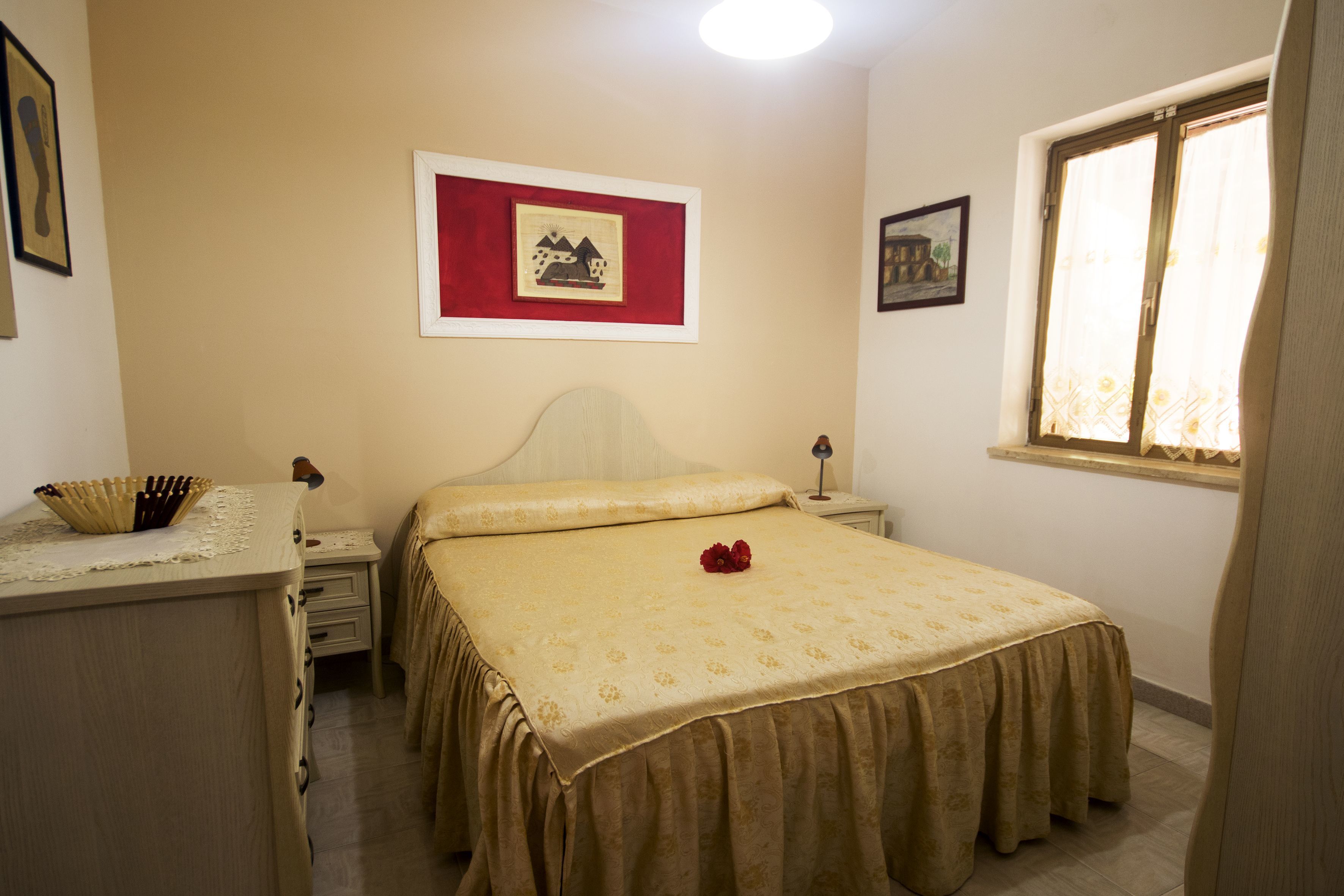 Un dormitorio con cama, mesitas de noche, cortinas y decoración en la pared.