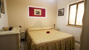 Un dormitorio con cama, mesitas de noche, cortinas y decoración en la pared.