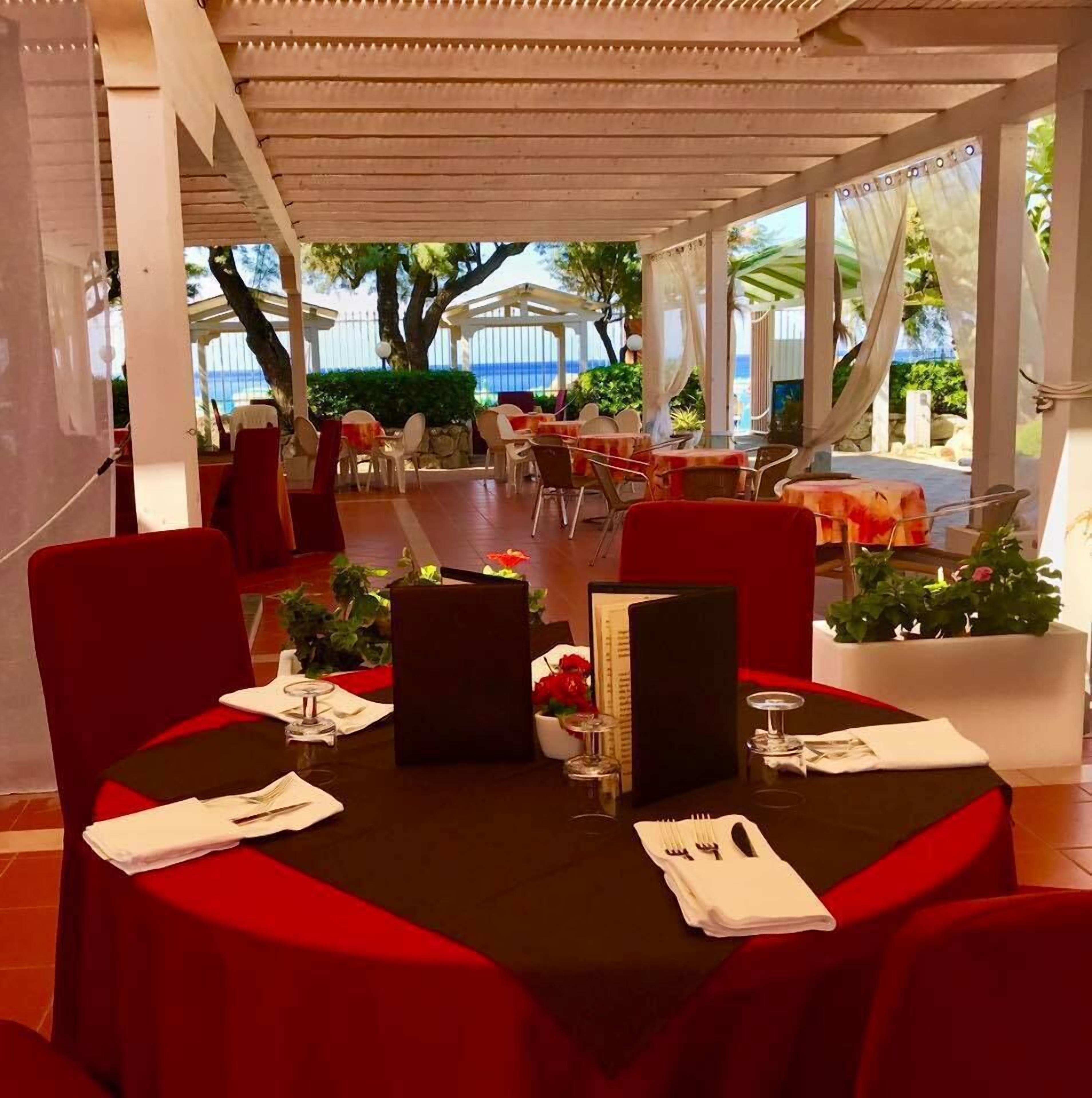 A restaurant with tables set for dining, featuring a view of the ocean.