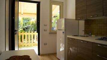 A compact kitchen with wooden cabinets, a white refrigerator, and a small window.