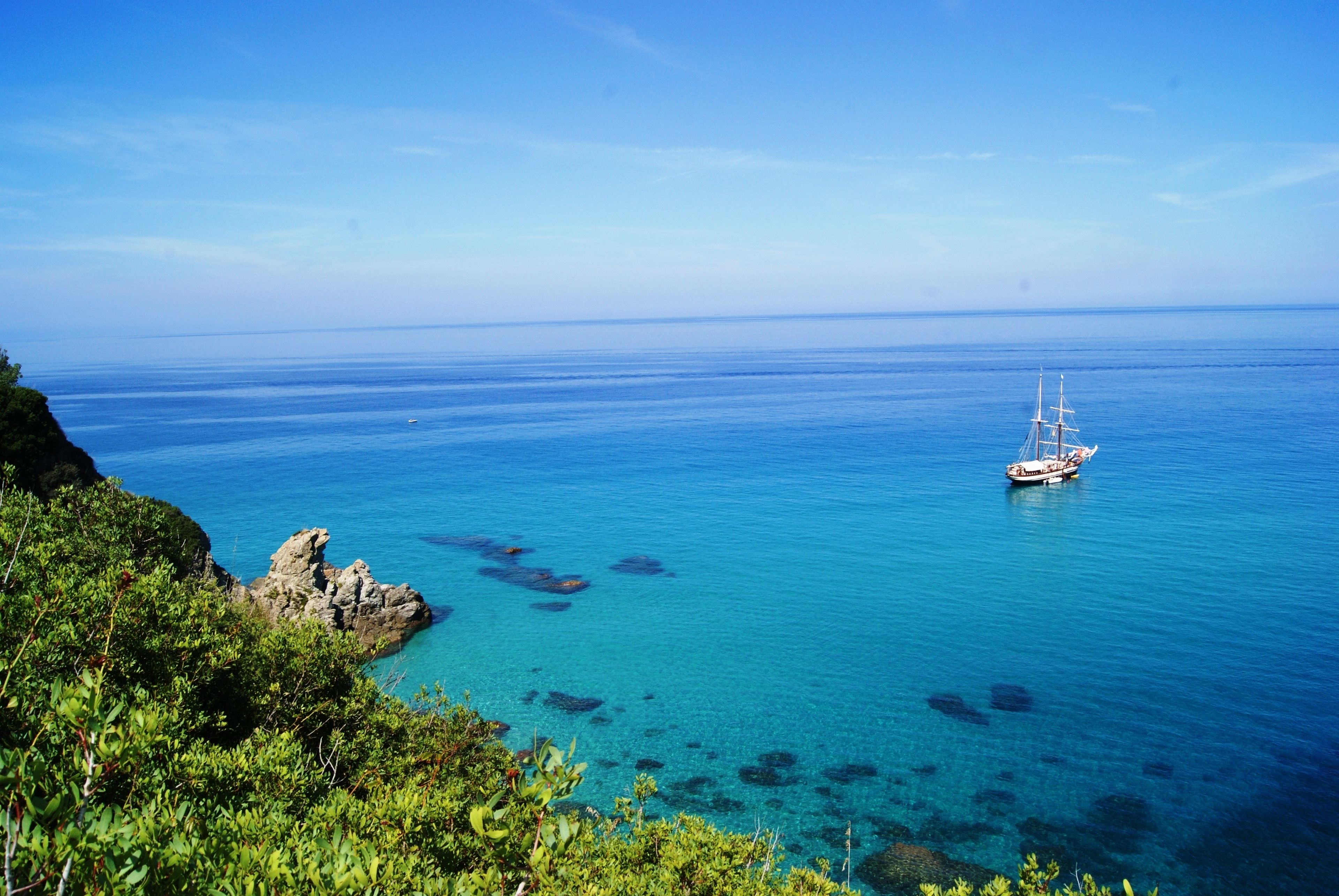 A coastal view with a boat on the water and rocky cliffs.