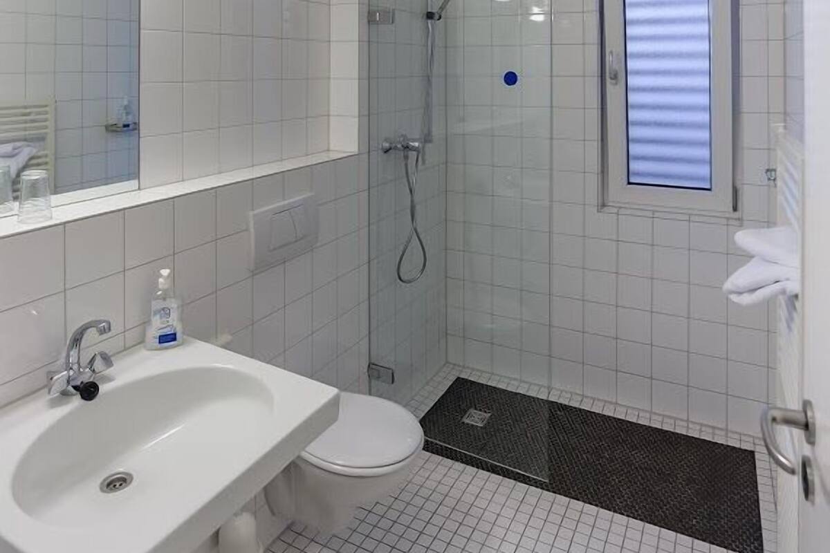 A modern bathroom with a white sink, toilet, and shower.
