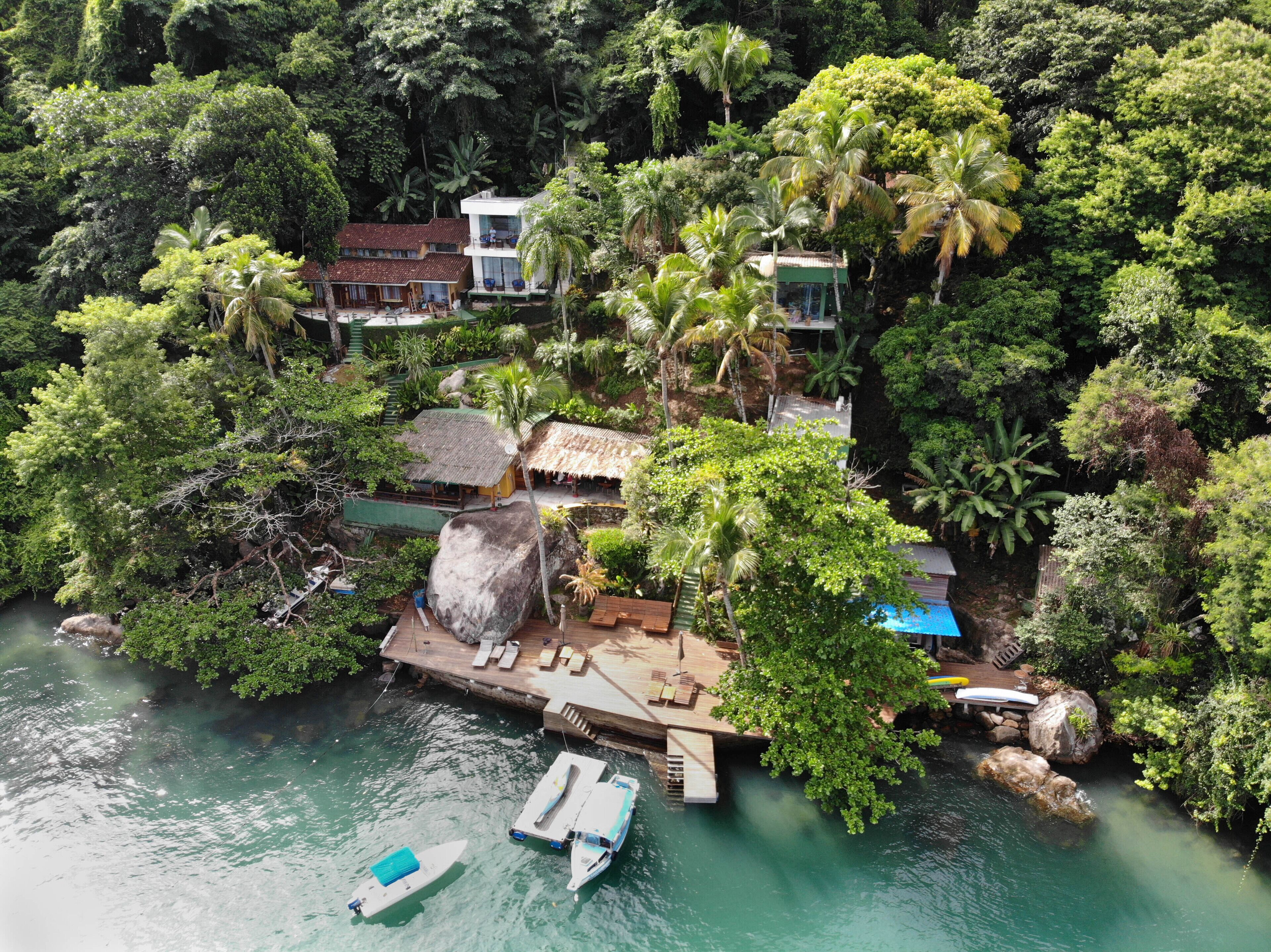 Um resort tropical com um cais, barcos e vegetação exuberante.