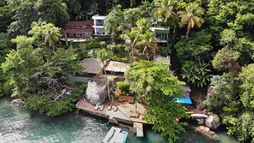 Um resort tropical com um cais, barcos e vegetação exuberante.