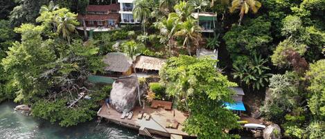 Un resort tropical con un muelle, embarcaciones y exuberante follaje.