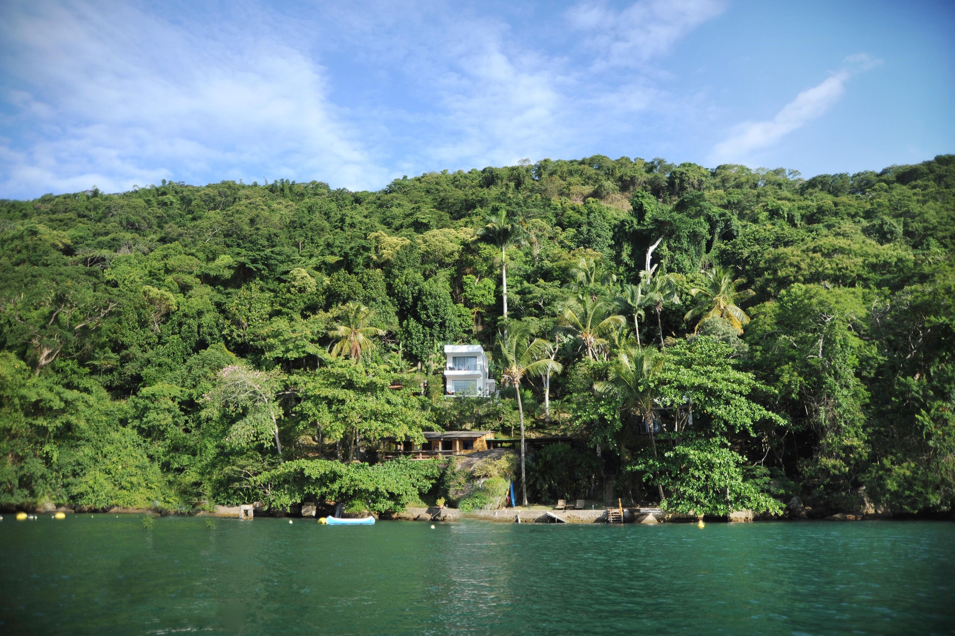 A tropical resort with a large house surrounded by dense greenery and a body of water.