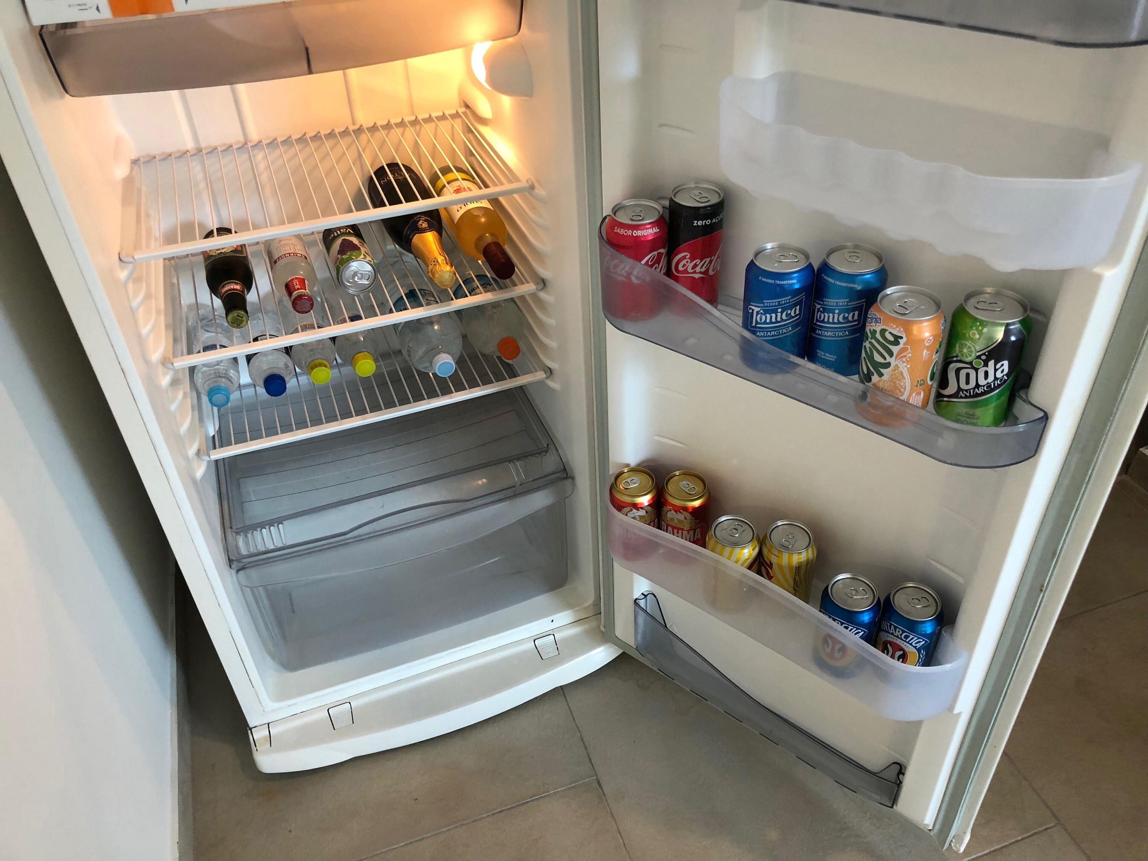 An open refrigerator with shelves stocked with beverages and bottles.