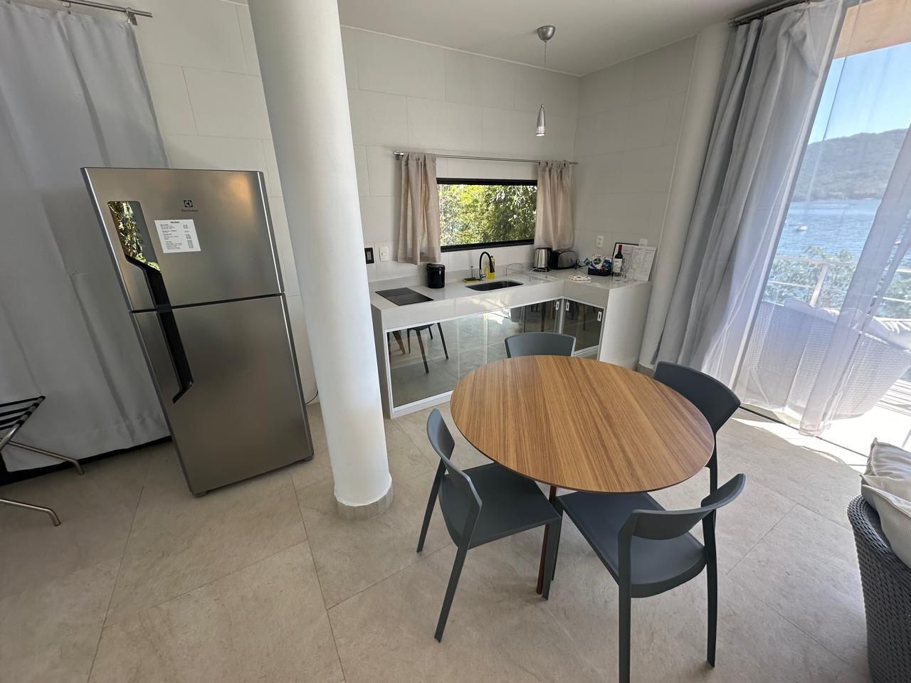 A modern kitchen with a refrigerator, sink, and dining area with chairs.